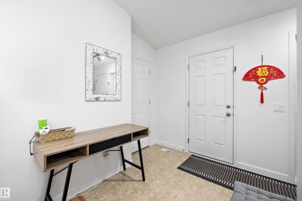 Interior entryway with a modern desk, a decorative mirror, and a white front door. - 3344 24 Av Nw, Edmonton