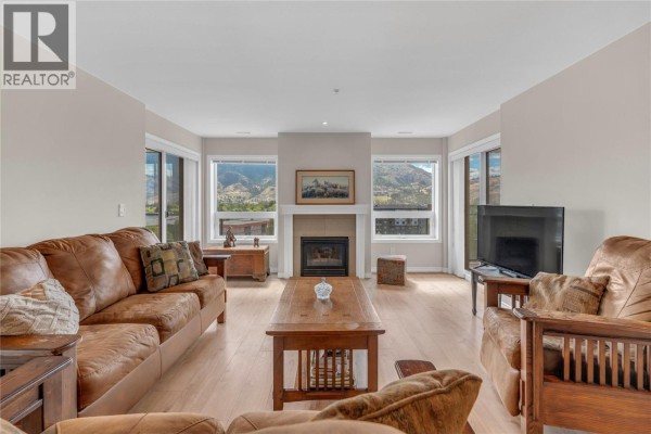 Kitchen with stainless steel appliances, wood cabinets, and island seating. - 3346 Skaha Lake Road Unit# 804, Penticton