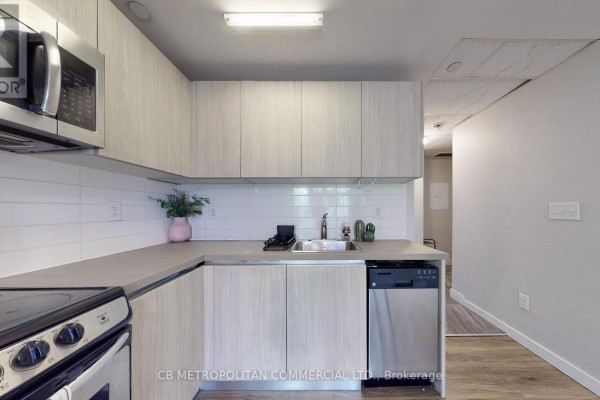 Living space with a sofa, coffee table, desk, television, and loft bedroom above. - 335 College Street, Toronto