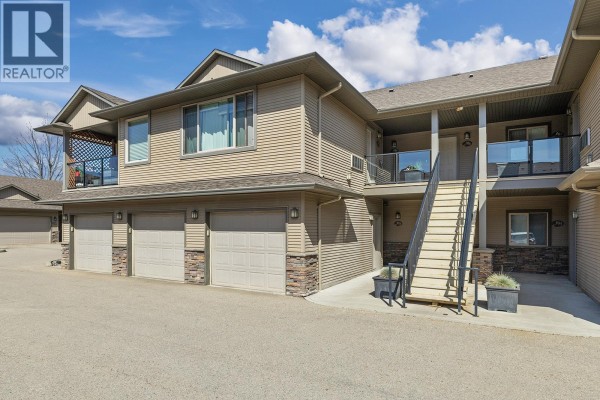 Side view of a townhouse complex showing garage doors, exterior stairs, and balconies. - 3350 Woodsdale Road Unit# 401, Lake Country