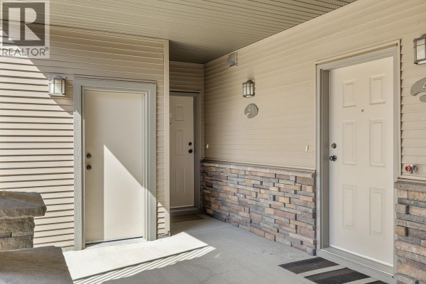 Exterior view of townhouse building entrances with beige doors and stone accents. - 3350 Woodsdale Road Unit# 401, Lake Country