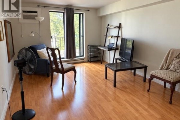 View from a balcony overlooking the parking lot and green trees. - 3355 Sandwich Street Unit# 304, Windsor