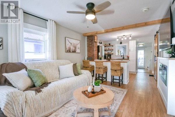 Living room with a beige sofa, coffee table, and kitchen island with bar stools. - 3358 Muskoka Street, Severn