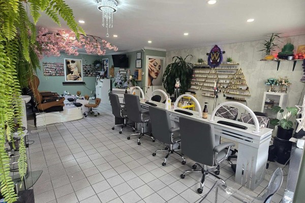 Nail salon interior with multiple manicure stations, pedicure chairs, and shelves of polish. - 336 Weston Road, Toronto