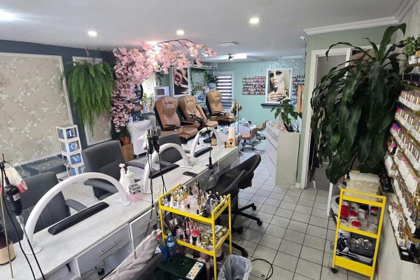 Spacious nail salon with manicure tables, pedicure chairs, and shelves stocked with nail polish. - 336 Weston Road, Toronto