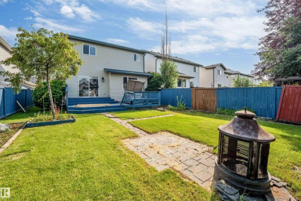 Front entrance of a beige two-story house with a concrete walkway and green lawn. - 336 Wild Rose Wy Nw, Edmonton