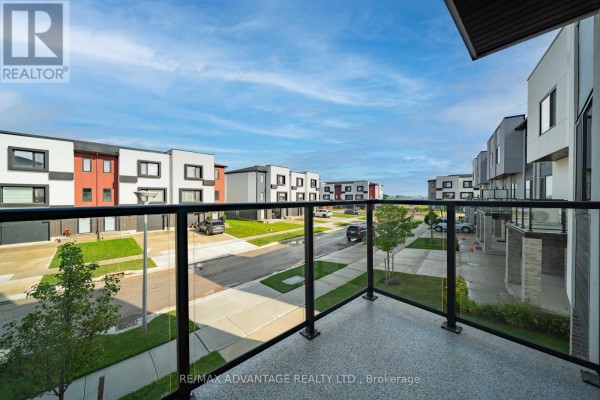 View from balcony of street with townhouses and cars under a blue sky. - 3363 David Milne Way, London South