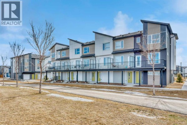 Row of modern townhouses with varied siding and balconies under a blue sky. - 337, 301 Redstone Boulevard Ne, Calgary