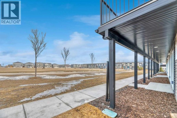 Underneath a balcony with black pillars and a sidewalk leading to a building entrance. - 337, 301 Redstone Boulevard Ne, Calgary