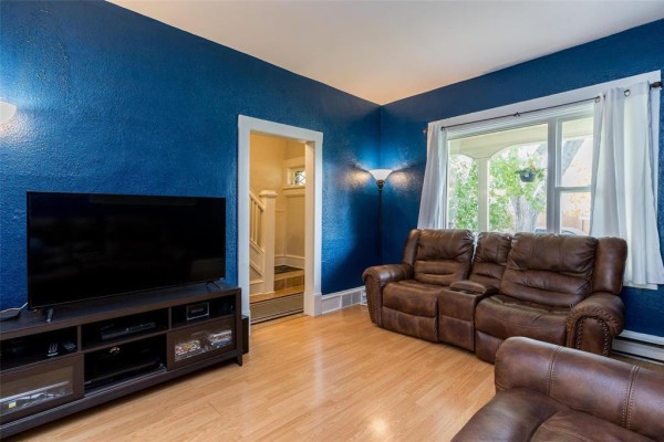 Living room with blue walls, leather couches, television, and window with white curtains. - 337 Bannerman Avenue, Winnipeg