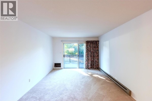 Living room with beige carpet, white walls, sliding glass door with floral curtains. - 337 Mckinney Road Unit# 107, Oliver