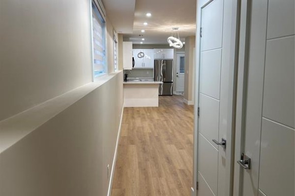 Hallway view towards a modern white kitchen with stainless steel appliances. - 3371 Byng Unit# 2, Windsor