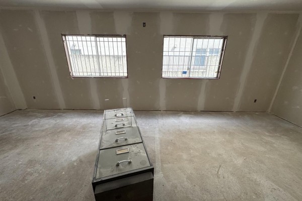 Room with concrete floor, drywall walls, and two windows with metal bars, featuring a metal filing cabinet. - 33719 Essendene Avenue, Abbotsford