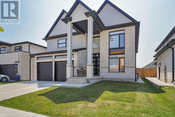 Side view of the modern house showing the garage, entrance, and lawn. - 3373 Regiment Road, London South
