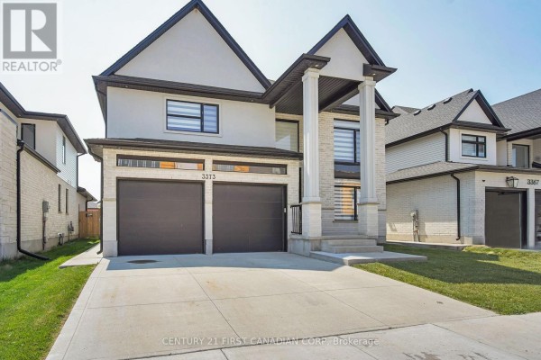Front view of the house from the driveway, highlighting the two garage doors and architectural details. - 3373 Regiment Road, London South