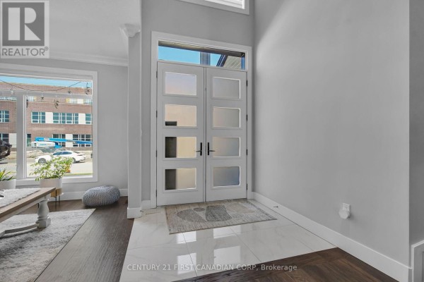 Interior view of the foyer facing the double front doors, with tile flooring and a window. - 3373 Regiment Road, London South