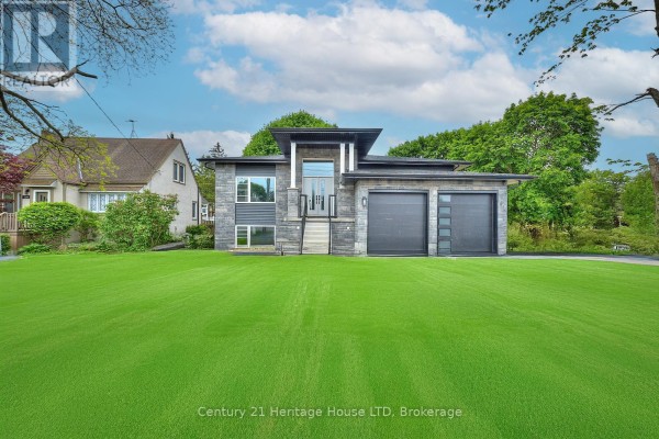 Modern home exterior with stone siding, two garage doors, and a manicured lawn under a cloudy sky. - 338 Sugarloaf Street, Port Colborne
