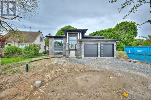 Contemporary house exterior with grey stone and metal siding, undergoing landscaping with visible construction materials. - 338 Sugarloaf Street, Port Colborne