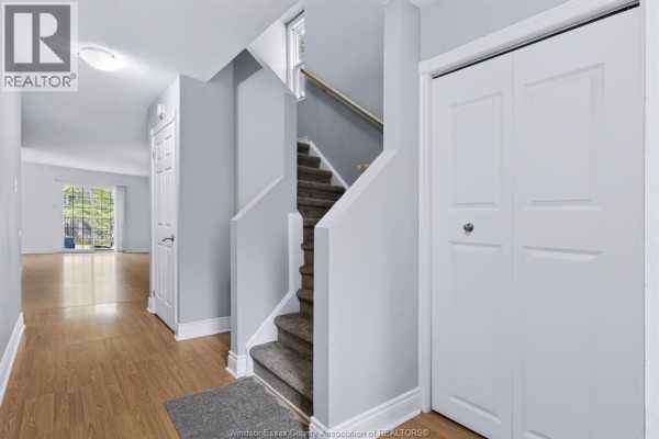 View of an interior hallway leading to a brightly lit living area with large windows and patio doors. - 3380 South Millway Unit# 44, Mississauga