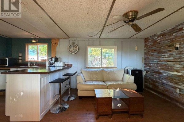 Bedroom with a bed, two windows, wood-paneled walls, and a floor lamp. - 33833 Hessenland Lane, Bluewater
