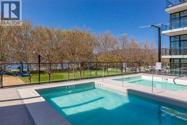 Outdoor swimming pools and hot tubs with a view of the lake and trees. - 3389 Lakeshore Road Unit# 413, Kelowna