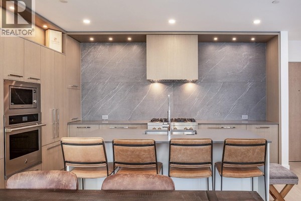Modern kitchen with stainless steel appliances, waterfall island, and light wood cabinetry. - 3389 Lakeshore Road Unit# 413, Kelowna