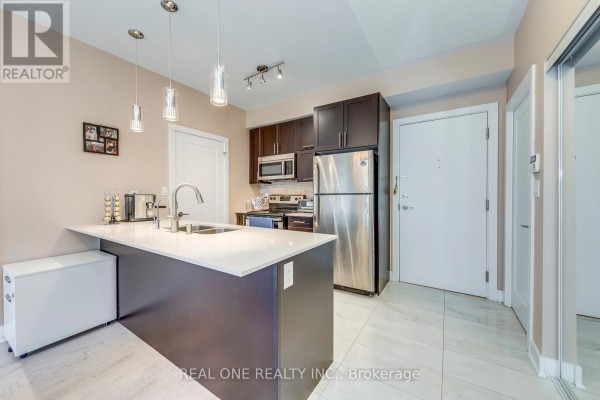 Kitchen with dark brown cabinets, white quartz island and stainless steel appliances. - 339 - 28 Prince Regent Street, Markham