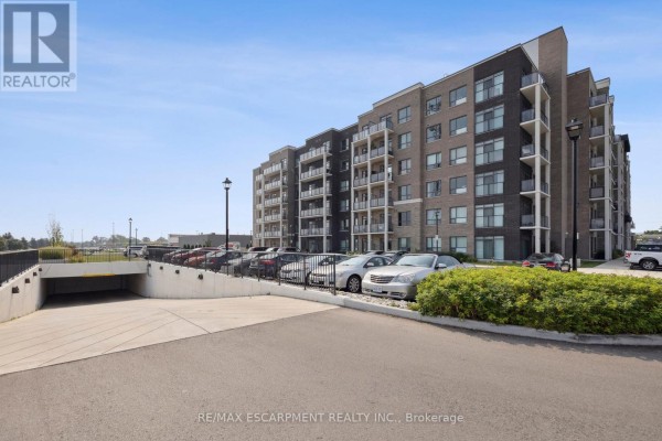 View of an apartment building exterior and an underground parking garage entrance on a paved lot. - 339 - 5055 Greenlane Road, Lincoln