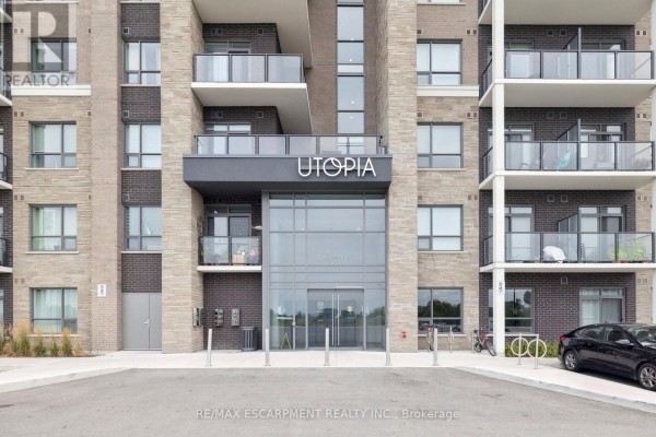 Main entrance to the UTOPIA apartment building with glass doors, brick facade, and balconies. - 339 - 5055 Greenlane Road, Lincoln