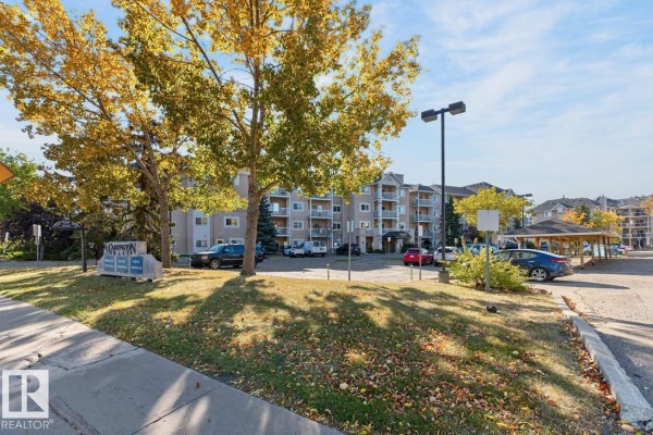 Exterior view of Carrington West apartment buildings with trees and parking lot. - #339 17447 98a Av Nw, Edmonton