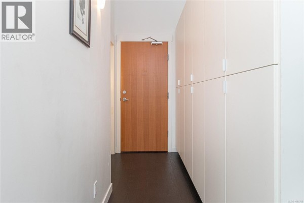 Interior hallway with a wooden door and a wall of tall white closets. - 339 770 Fisgard St, Victoria
