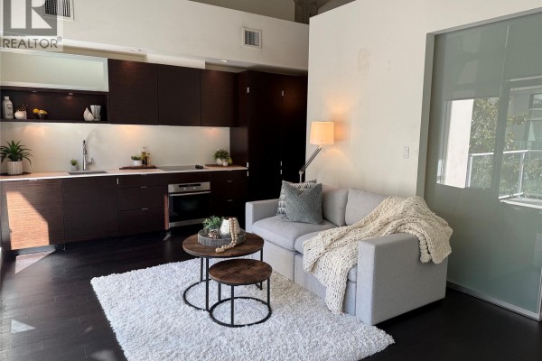 Living room with a large sectional sofa, coffee table, and modern kitchen. - 339 770 Fisgard St, Victoria