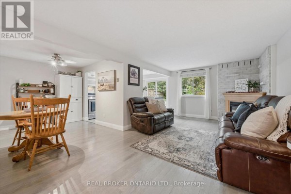 Open-concept living and dining area with a wooden table, sofa, and fireplace. - 339 Strathallan Street, Centre Wellington