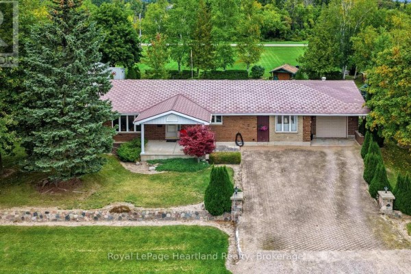 Aerial view of the brick ranch-style house with a large driveway and mature trees. - 33950 Bachand Street, Bluewater