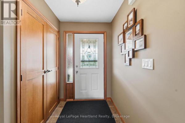 Interior entryway with tan walls, a white door with stained glass sidelight, and wood-paneled closet. - 33950 Bachand Street, Bluewater