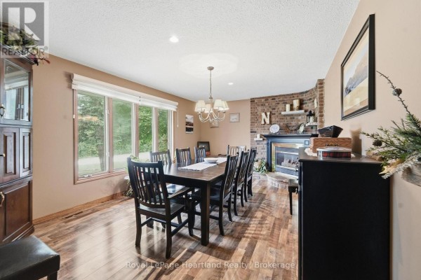 Formal dining room with a fireplace, large windows, wood floors, and a dark wood dining set. - 33950 Bachand Street, Bluewater