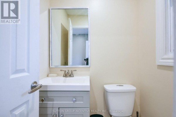 A small powder room with a vanity, sink, toilet, and silver-framed mirror. - 33b Cundles Road E, Barrie