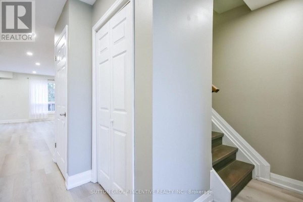 A hallway showing a closet, a staircase with dark wood steps, and grey walls. - 33b Cundles Road E, Barrie