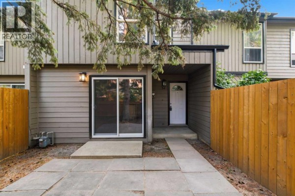Front exterior of townhouse with a patio, pathway, and front door visible. - 34, 420 Grier Avenue Ne, Calgary