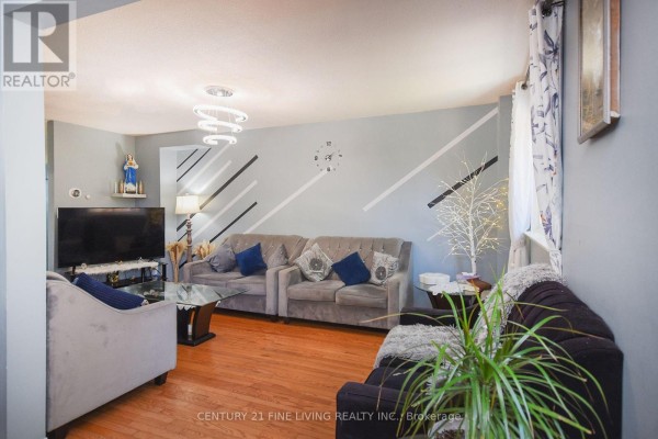 Living room with sofas, coffee table, hardwood floors, and a wall with diagonal stripes. - 34 - 2700 Battleford Road, Mississauga
