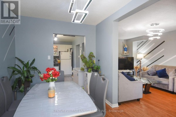 View from dining room showing entrance to kitchen and living room with sofas and hardwood floors. - 34 - 2700 Battleford Road, Mississauga