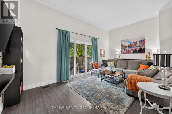 Living room with a sofa, coffee table, and sliding glass doors opening to a backyard. - 34 - 300 Sandringham Crescent, London South