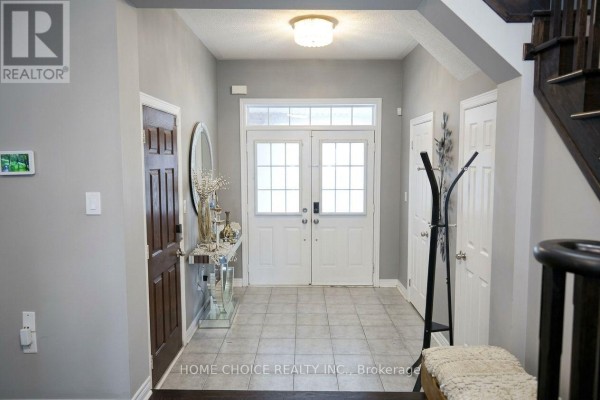 Interior foyer with gray walls, tiled floor, double doors, and a dark wood staircase. - 34 - 3275 Stalybridge Drive, Oakville