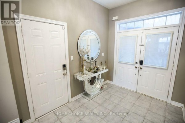Foyer with tiled floor, gray walls, double doors, and decorative console table with a round mirror. - 34 - 3275 Stalybridge Drive, Oakville