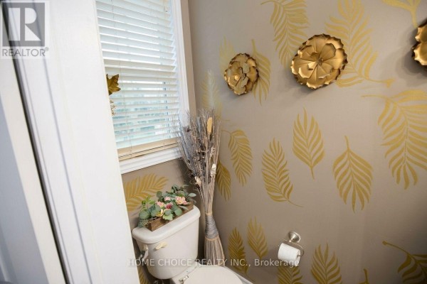 Powder room with beige walls, gold leaf pattern, toilet, and decorative wall art. - 34 - 3275 Stalybridge Drive, Oakville