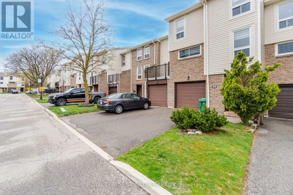 Street view of townhouses with driveways, garages, and parked cars. - 34 - 7251 Copenhagen Road, Mississauga