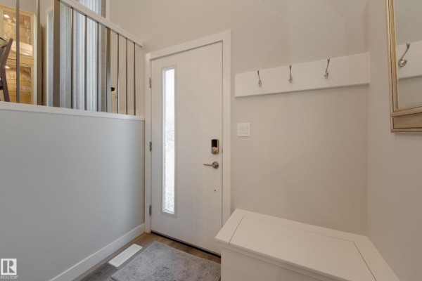 A bedroom with a king-sized bed, two nightstands, a chair, and large windows with white curtains. - #34 1729 Keene Cr Sw, Edmonton