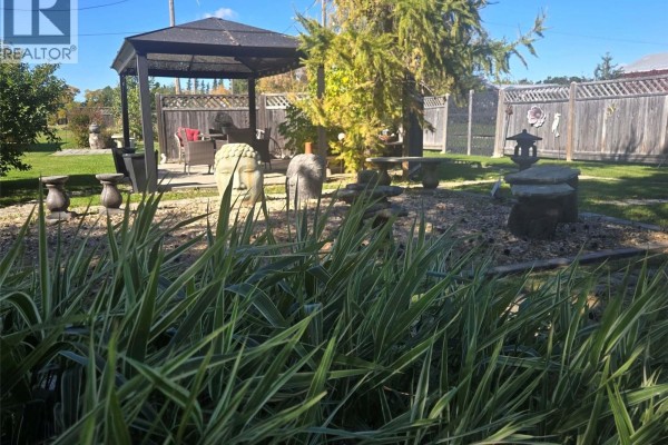 Covered gazebo with outdoor seating and garden statues in a landscaped yard. - 34 1st Street N, St Benedict