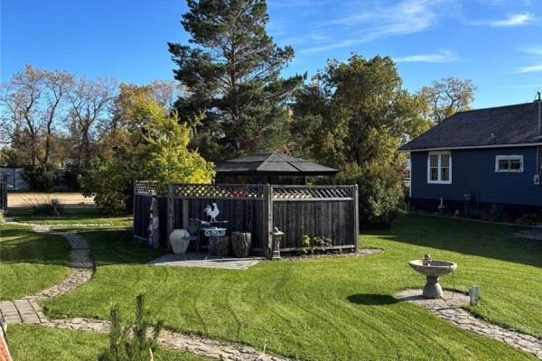 Backyard with a wooden fence, gazebo, pathways, and a small fountain. - 34 1st Street N, St Benedict