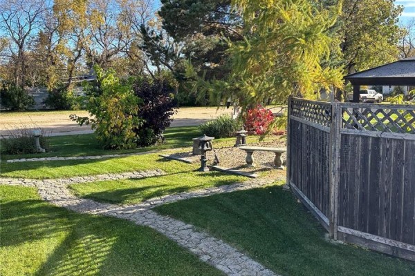 Yard with stone pathways, garden benches, and a fence surrounding the property. - 34 1st Street N, St Benedict